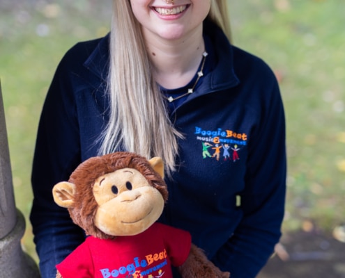 caitlin, long blonde hair and navy top holding a giggles the monkey