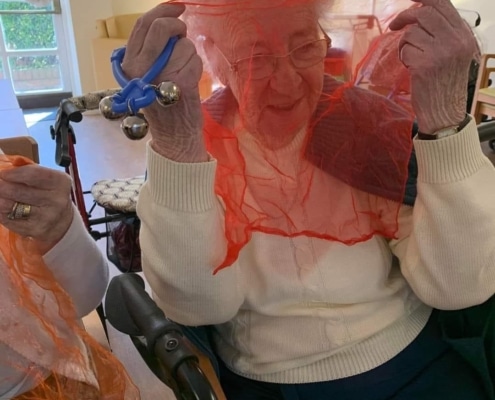 Lady with a scarf and shaker taking part in a Boogie Beat intergenerational activity