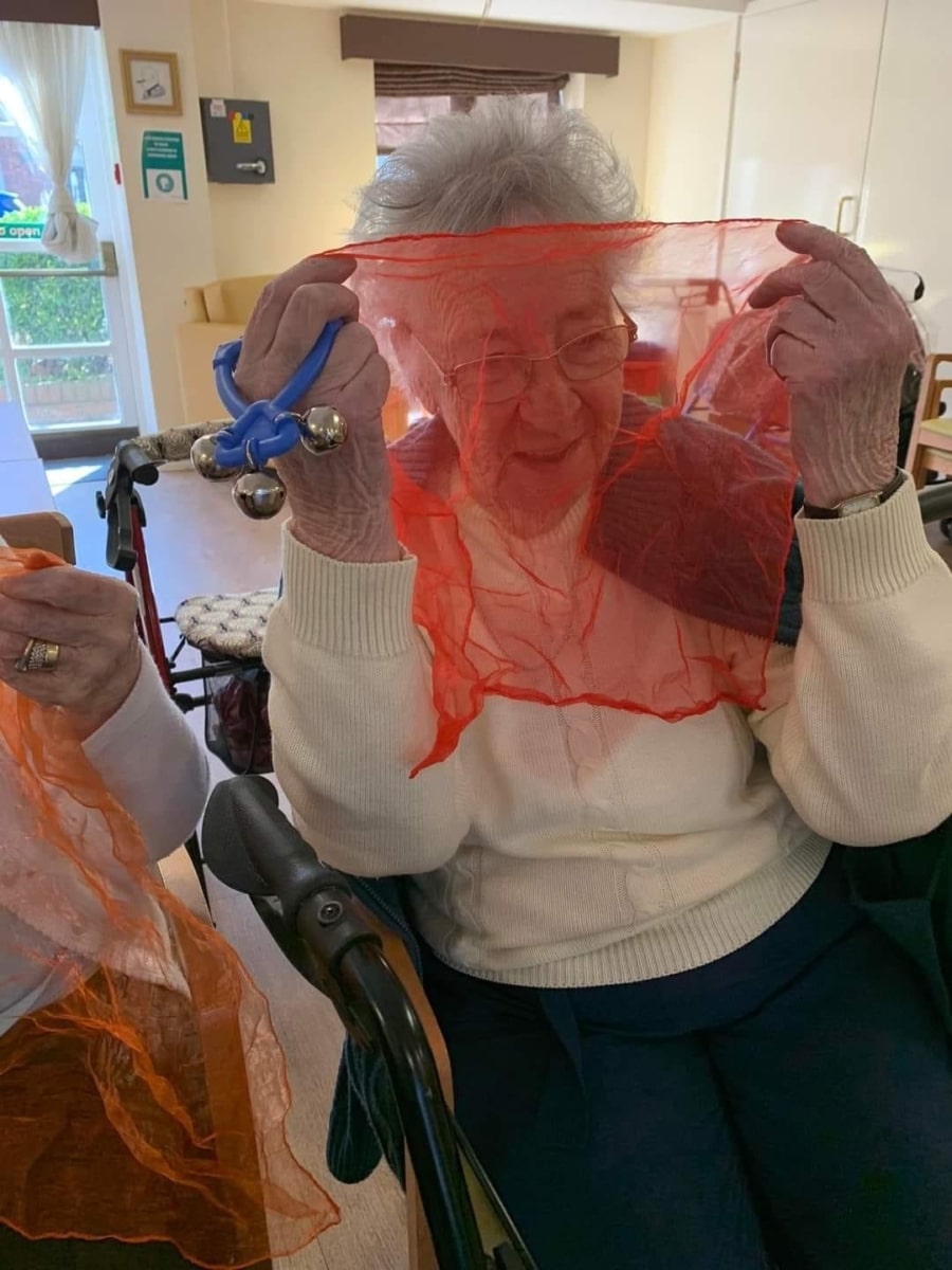 Lady with a scarf and shaker taking part in a Boogie Beat intergenerational activity