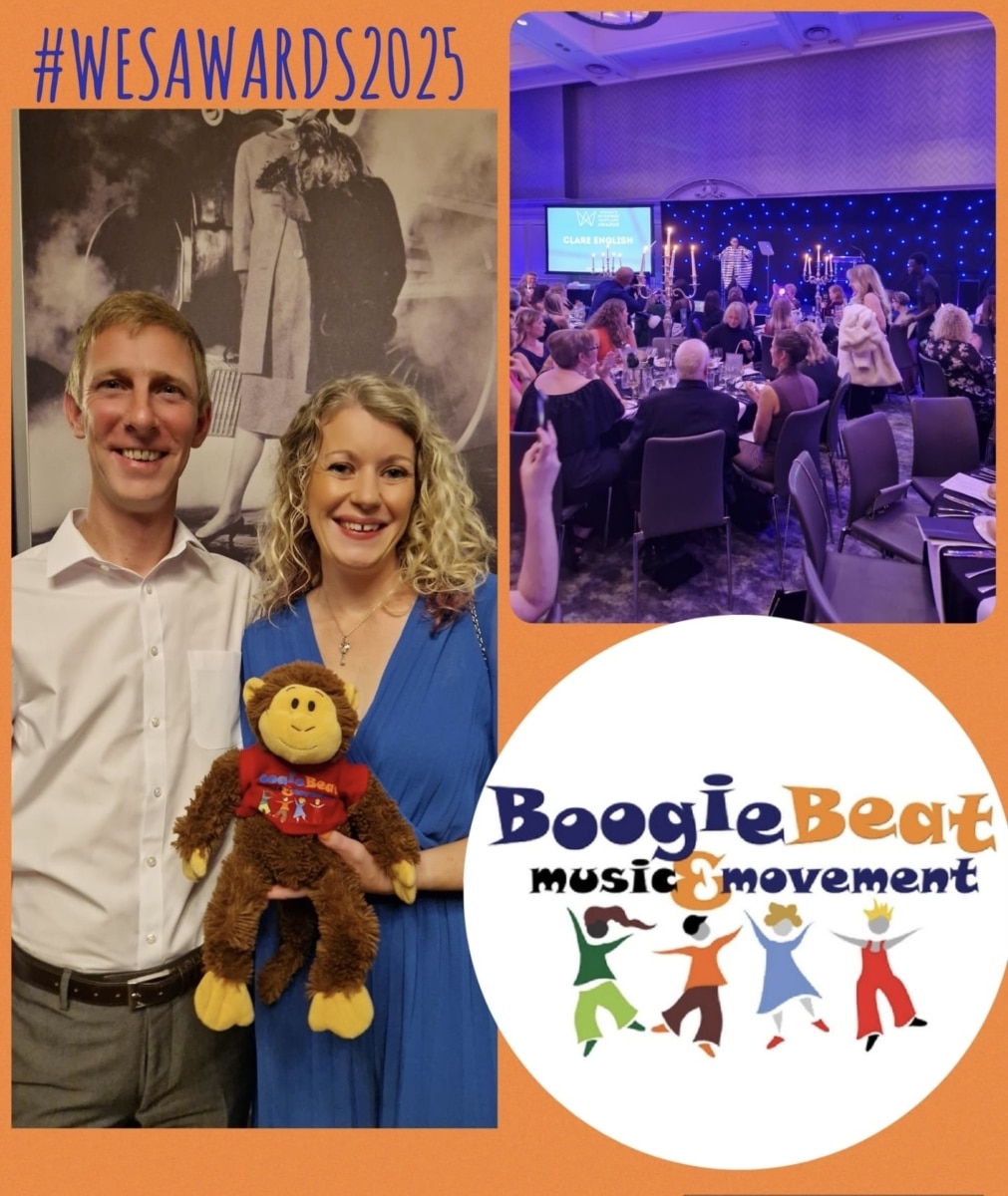 Lady in a blue dress holding a monkey soft toy with a man in a white shirt attending an awards event