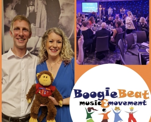 Lady in a blue dress holding a monkey soft toy with a man in a white shirt attending an awards event