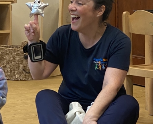 lady with brown hair tied back holding a star and singing